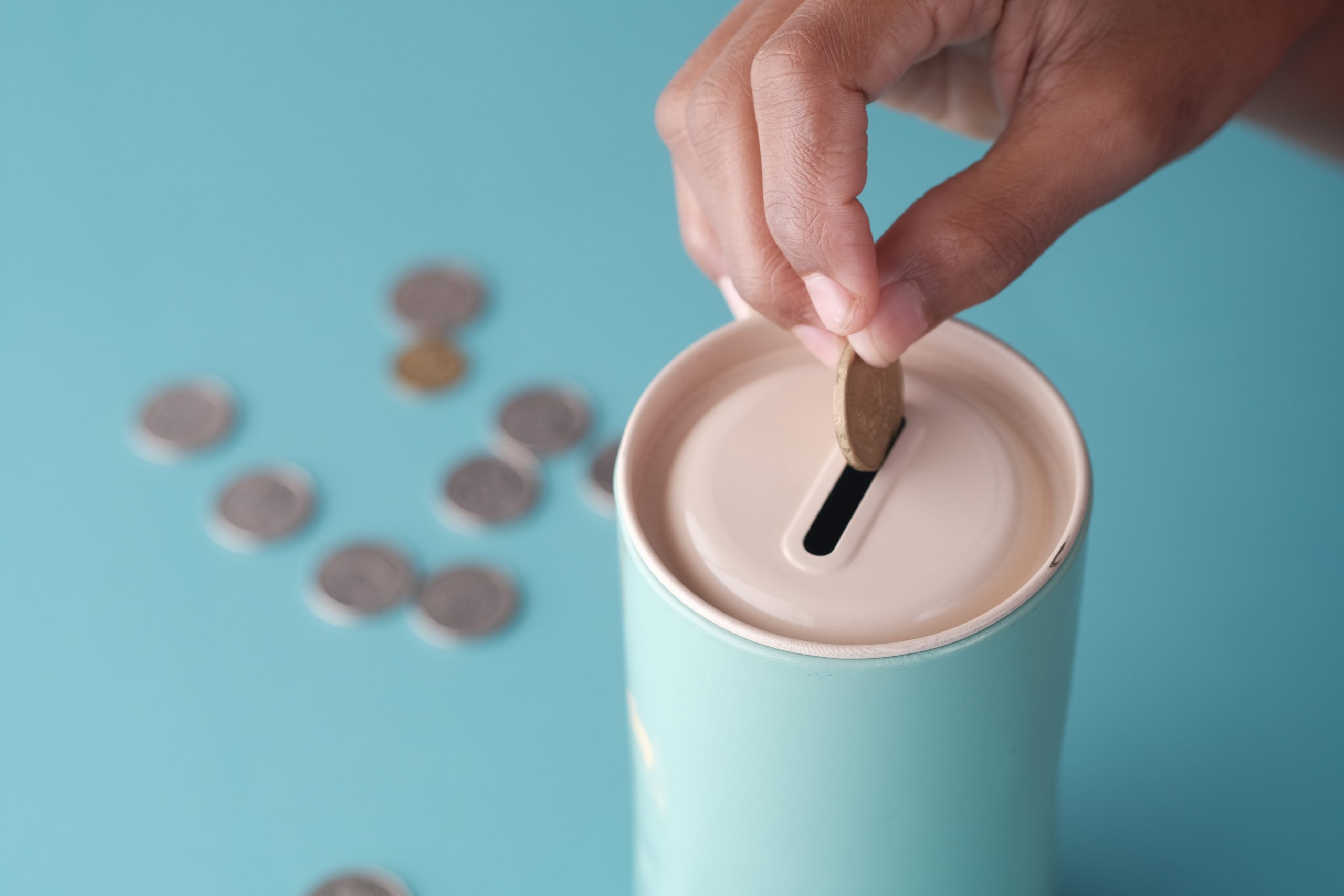 A hand puts a coin into a tin 